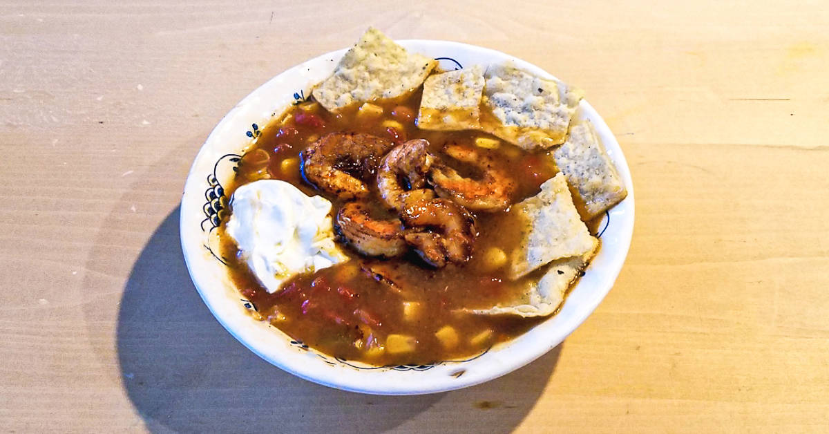 shrimp taco soup soup plated with tortilla strips and sour cream